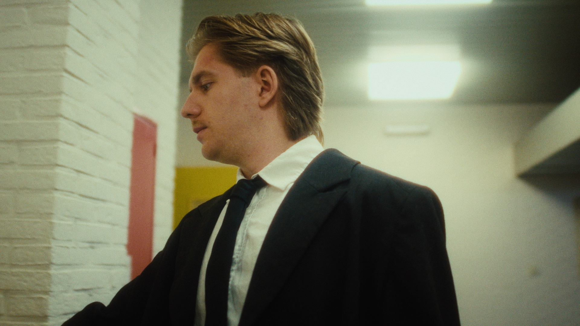 Man in a suit in a bare corridor, from Dark Desire